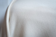 Close-up of white fabric with a textured pattern on a light gray background