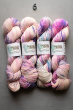 Load image into Gallery viewer, Four skeins of multicolored yarn with visible brand labels on a gray background