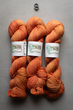 Load image into Gallery viewer, Three skeins of orange yarn with labels on a gray background