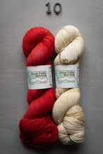 Load image into Gallery viewer, Two skeins of yarn, one red and one beige, with labels on a gray background.