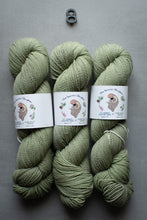 Load image into Gallery viewer, Three skeins of green yarn with labels on a gray background