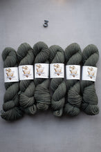 Load image into Gallery viewer, Six skeins of dark gray yarn with labels on a gray background