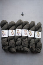 Load image into Gallery viewer, Gray yarn skeins with labels on a gray background