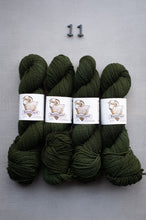 Load image into Gallery viewer, Four skeins of green yarn with labels on a gray background