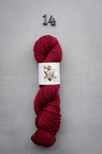 Load image into Gallery viewer, Red skein of yarn with a label on a gray background
