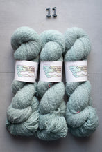 Load image into Gallery viewer, Three skeins of light blue yarn with labels on a gray background