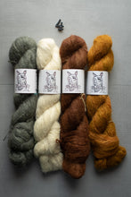 Load image into Gallery viewer, Four skeins of yarn in gray, white, brown, and orange on a gray background with labels.