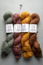 Load image into Gallery viewer, Four skeins of yarn in green, pink, yellow, and brown on a gray background with labels.