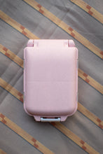 Load image into Gallery viewer, A light pink hard-shell lunch box with a secure clasp closure, photographed from directly above on a striped fabric surface.