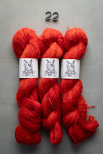 Load image into Gallery viewer, Three skeins of red yarn with labels on a gray background