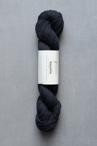 Dark gray skein of yarn with a label on a gray background