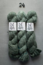 Load image into Gallery viewer, Three skeins of green yarn with labels on a gray background