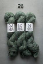 Load image into Gallery viewer, Three skeins of green yarn with labels on a gray background