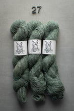 Load image into Gallery viewer, Three skeins of green yarn with labels on a gray background