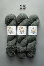 Load image into Gallery viewer, Three skeins of gray yarn with labels on a gray background