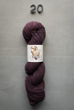 Load image into Gallery viewer, Purple skein of yarn with a label on a gray textured background