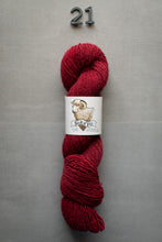 Load image into Gallery viewer, Red skein of yarn with a label on a gray background