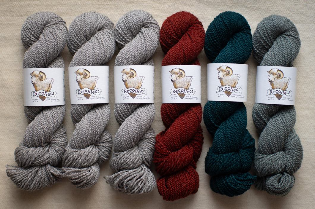 Six skeins of yarn in gray, red, and green on a beige surface with 'Bee & Wolf' labels.