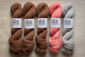 Five skeins of yarn in brown, pink, and gray on a neutral background with labels.