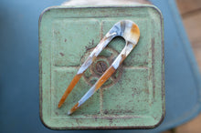 Load image into Gallery viewer, Rust-colored tongs on a green metal surface with a blurred background