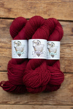 Load image into Gallery viewer, Three skeins of red yarn with 'Pishkun' labels on a wooden background