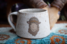 Load image into Gallery viewer, Ceramic mug with a sheep design wearing a crown on a textured surface.