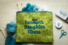 Load image into Gallery viewer, Green pouch with &#39;Farmer&#39;s Daughter Fibers&#39; branding, surrounded by yarn and knitting tools on a wooden surface.
