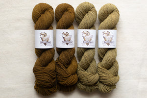 Four skeins of yarn in brown and green shades with labels on a light background