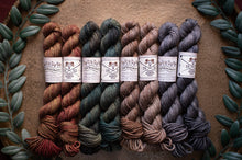 Load image into Gallery viewer, Set of yarn skeins in various colors with labels on a textured surface.