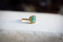 Load image into Gallery viewer, Gold ring with a green gemstone on a textured surface