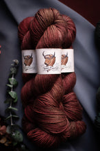 Load image into Gallery viewer, Red skein of yarn with a label on a dark background