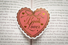 Load image into Gallery viewer, Heart-shaped 'Book Lover' enamel pin on an open book