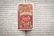Load image into Gallery viewer, Pink book-shaped warning label with 'Slowburn' text on an open book