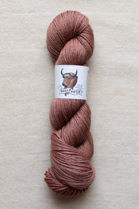 Ball of pink yarn with a label on a beige background