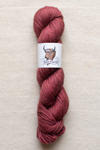 Load image into Gallery viewer, Red skein of yarn with a label on a beige background