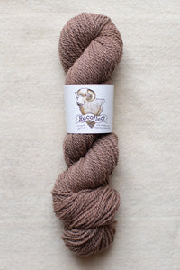 Brown skein of yarn with a label on a beige background