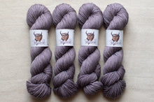 Load image into Gallery viewer, Four skeins of purple yarn with labels on a beige background