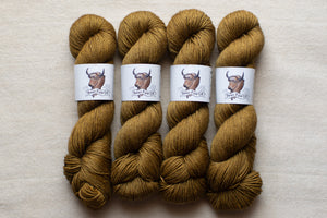 Four skeins of brown yarn with labels on a beige background