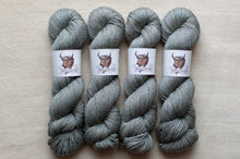 Load image into Gallery viewer, Four skeins of gray yarn with labels on a beige background
