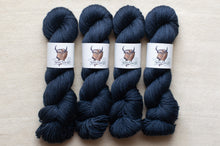 Load image into Gallery viewer, Four skeins of dark blue yarn with labels on a beige background