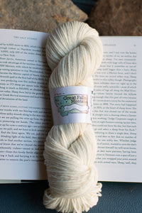 Skein of cream-colored yarn with a label on an open book