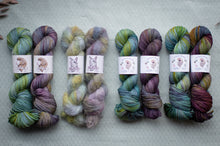 Load image into Gallery viewer, Five skeins of multicolored yarn with labels on a light gray background