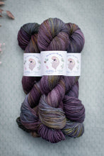 Load image into Gallery viewer, Two skeins of purple yarn with a label on a textured gray background