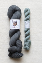 Load image into Gallery viewer, Two skeins of yarn, one gray and one green, on a light background with labels.