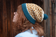 Load image into Gallery viewer, Person wearing a patterned beanie with blue trim against a wooden background