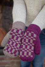 Load image into Gallery viewer, A close-up of a person holding a pair of hand-knit winter mittens. The mittens feature a purple and cream checkerboard pattern on the back of the hand with solid purple cuffs and purple fingertips, worn over a cream knit sweater and blue jeans.