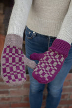 Load image into Gallery viewer, A person wearing knitted mittens in a real setting, with blue jeans and a cream sweater visible. The mittens are the product: one mitten is shown palm-side in mauve and cream, and the other is shown back-side in purple and cream with a checker pattern and solid purple cuff.