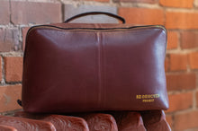 Load image into Gallery viewer, Brown leather pouch with 'RE:DESIGNED PROJECT' branding against a brick wall background