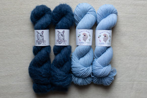 Four skeins of blue yarn on a beige surface with labels.