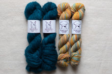 Load image into Gallery viewer, Two skeins of teal yarn and two skeins of multicolored yarn with visible labels on a light gray background.